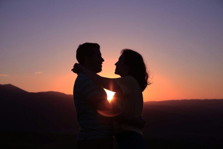 Silhouette of a couple embracing with a sunset in the background, creating a warm and romantic atmosphere, captured perfectly by LoveFlame.