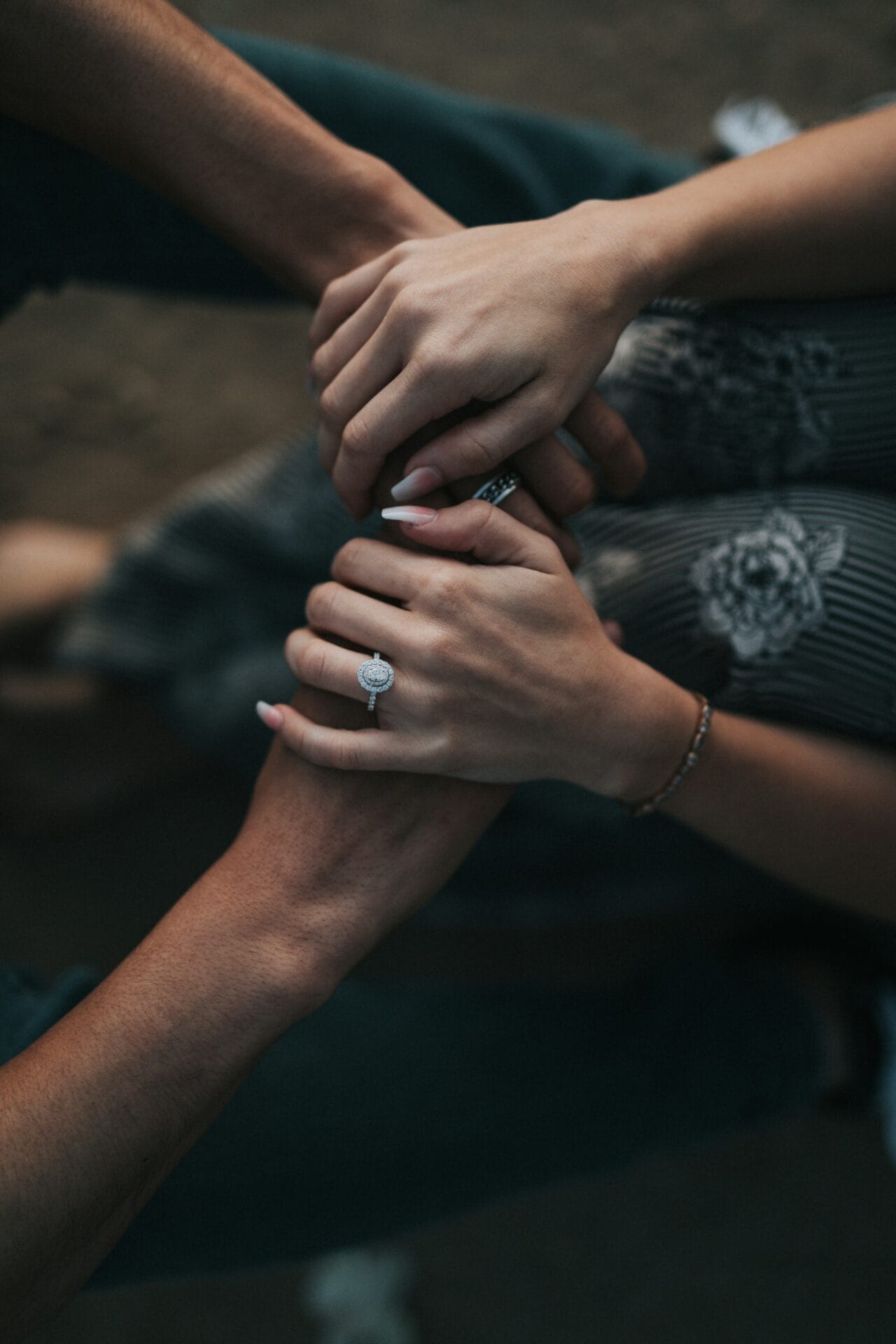 An engaged couple holding hands. Woman's hands holding her man's hands. Intimate moment in a couple.