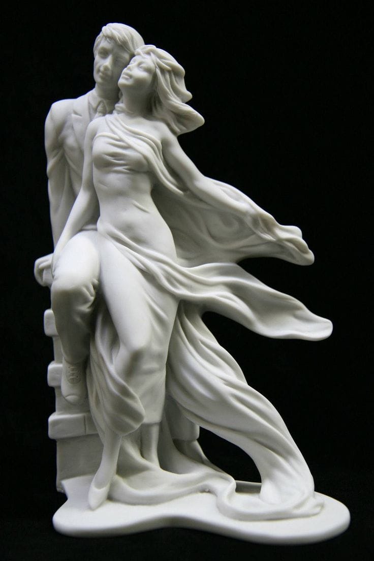 A white marble statue portrays a man in a suit and a flowing-robed woman, both gazing upward, their expressions hinting at the complexities of relationships and diverse types of sexuality.