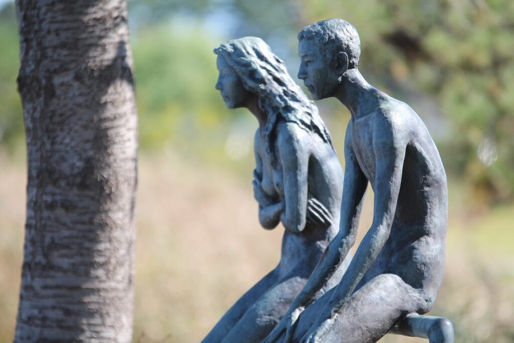 A sculpture of a man and woman sitting next to eath other without touching or looking at each other. A woman is crossing her hands as a sign of being frustrated. A man is sitting sadly. The sculture illustrates a wall between two people, a barrier in their intimacy. 